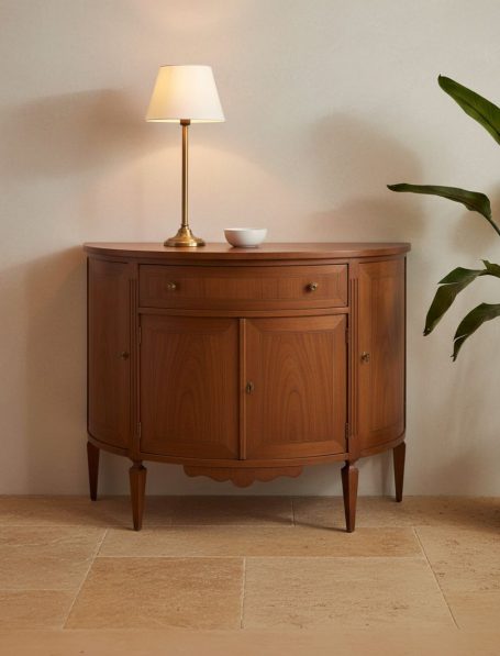 Holztisch, halbmondförmig, mit einer Lampe und einer Pflanze im Hintergrund.