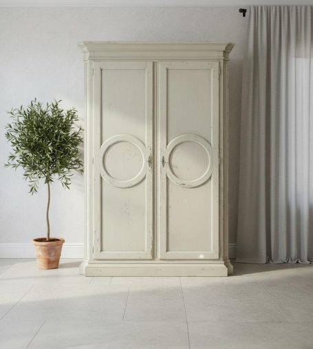 Beige Kleiderschrank mit runden Griffen neben einem kleinen Pflanze in einem Topf.