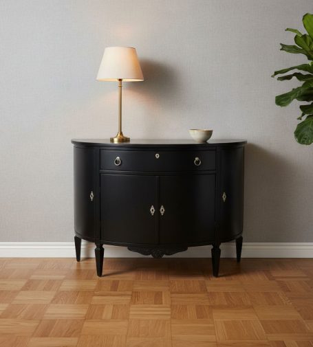 Schwarzer Konsolentisch mit Lampe und dekorativem Geschirr, vor einem grauen Wandhintergrund.