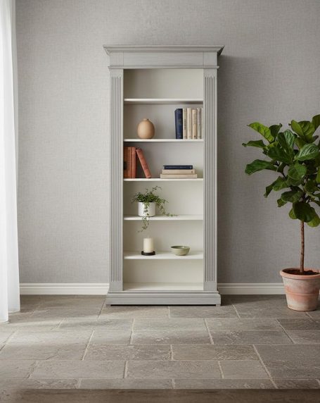 Heller Bücherregal mit mehreren Regalen und einer Pflanze im Topf daneben.